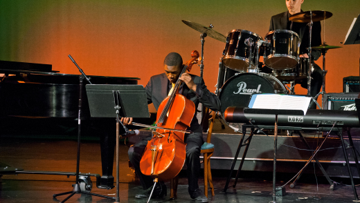 Male student playing a solo cello piece on stage