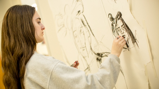 Female student drawing a portrait in charcoal