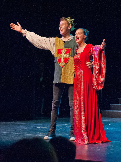 Male and female student performing on stage as king and queen