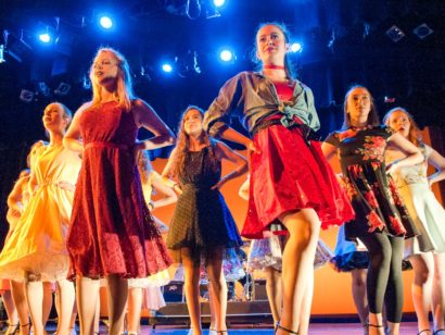 Group of female performers in costume dancing on stage