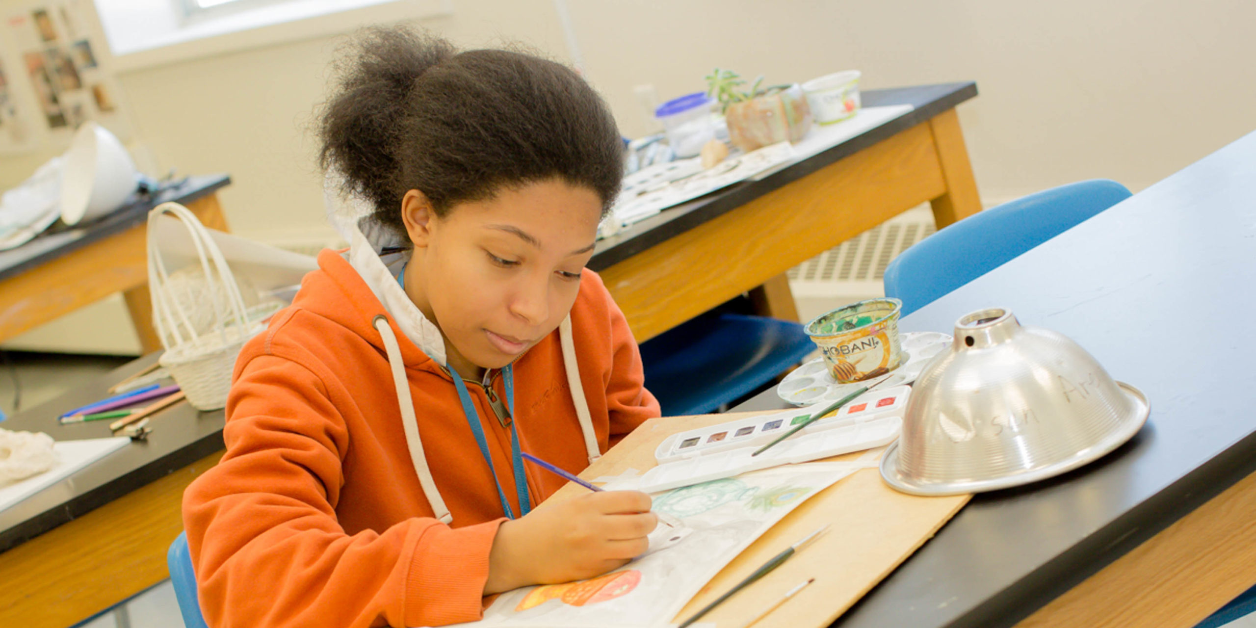 Art student drawing in class at a desk