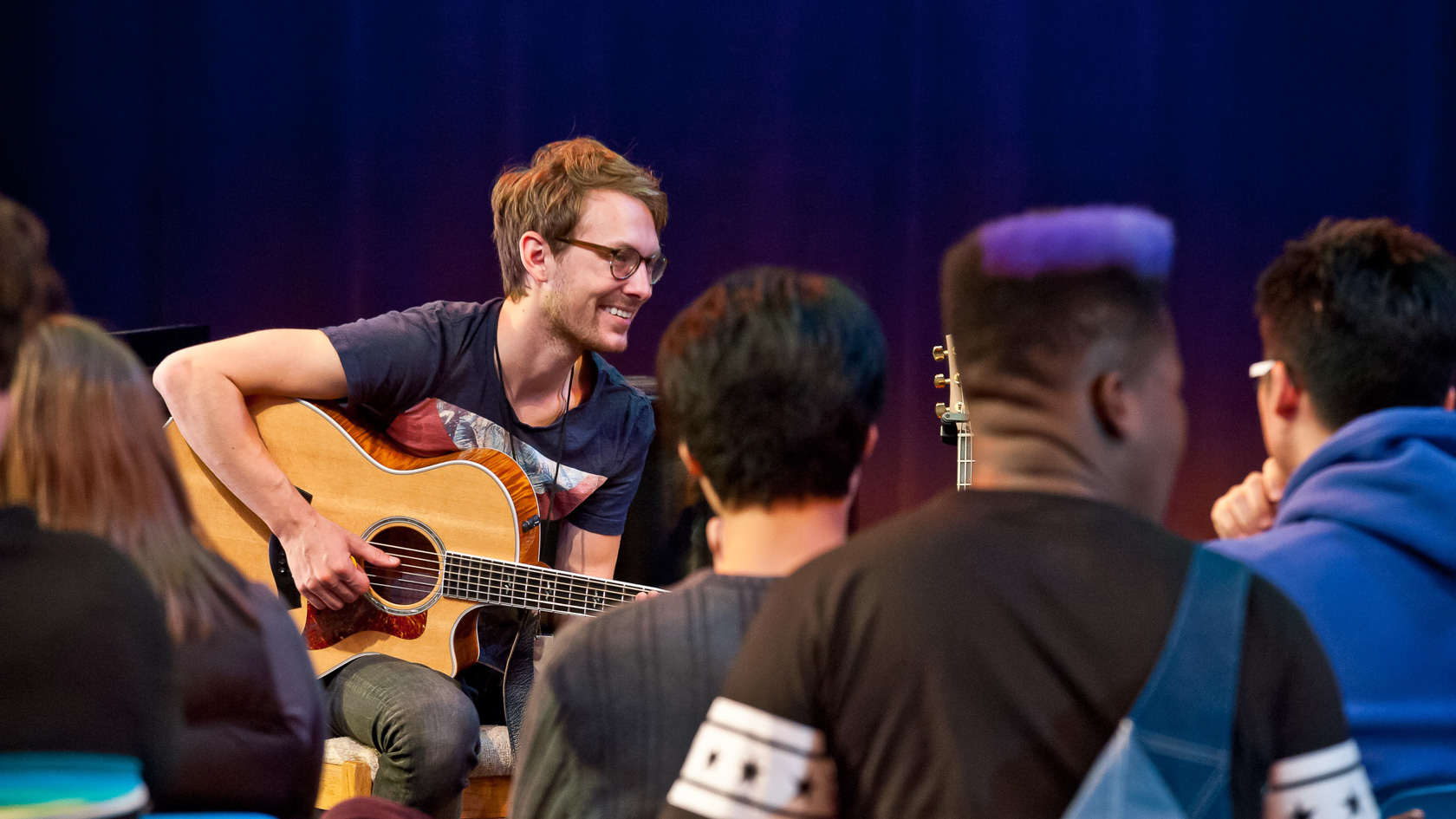 Music teacher playing guitar to a group of students