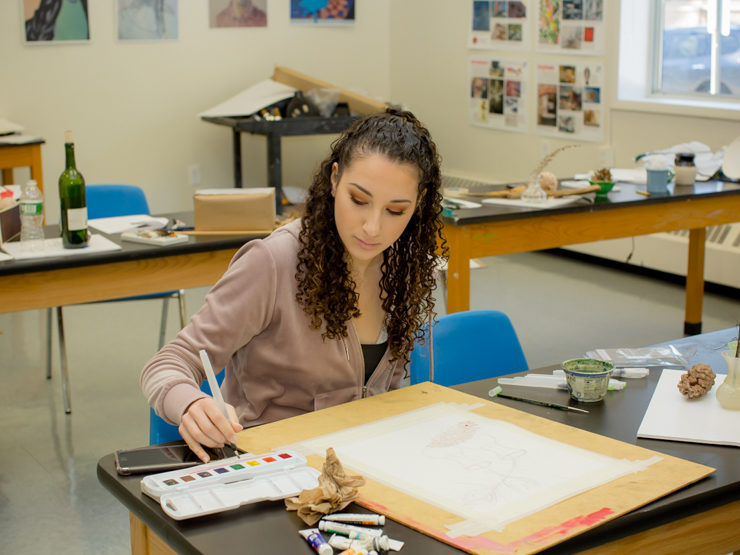 Female student painting with watercolor in class