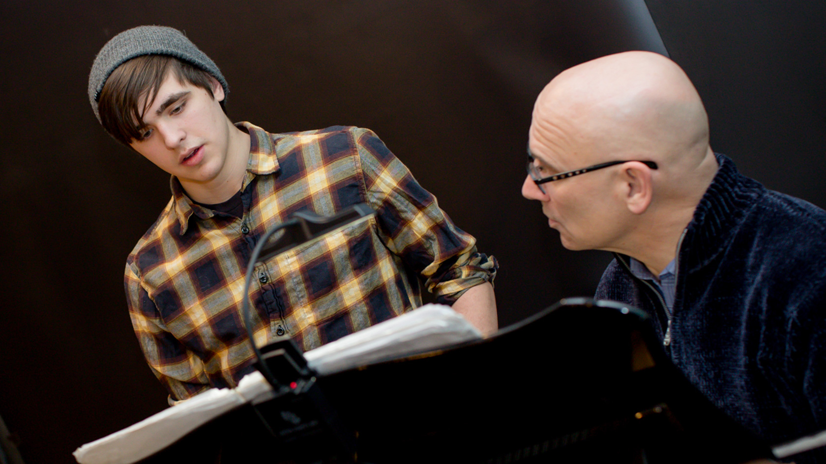 Student singing in class next to the teacher playing the piano