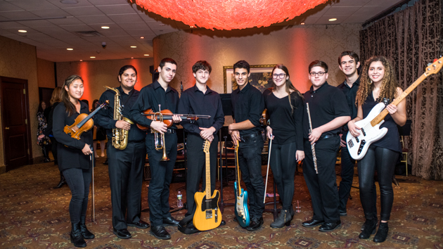 Group of student musicians standing together with their instruments before a performance