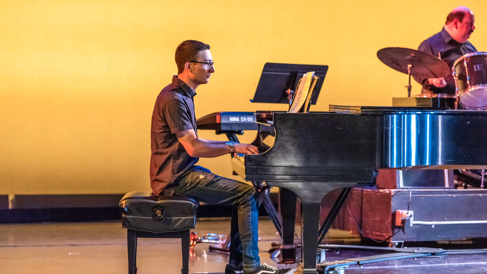 Male student playing the piano on stage