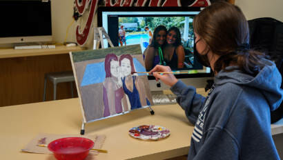 student painting a photo of her and her friend