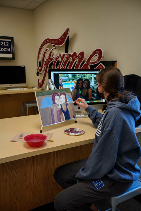 student painting a photo of her and her friend