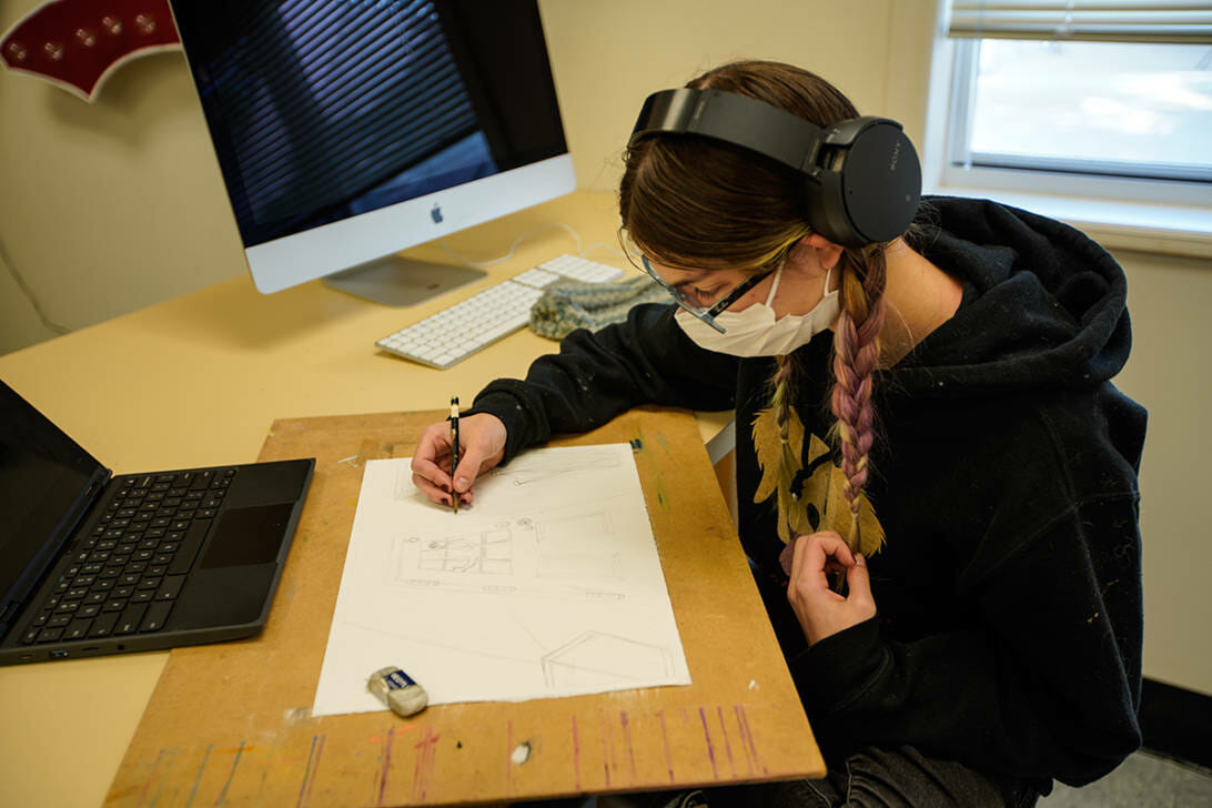 student wearing headphones and drawing