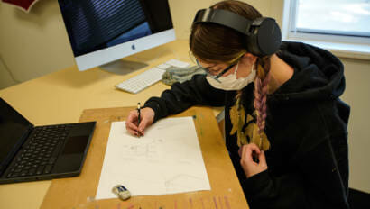 student wearing headphones and drawing