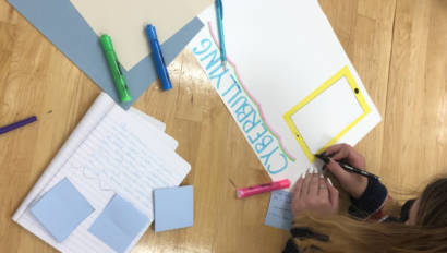 girls making signs to help prevent cyberbullying