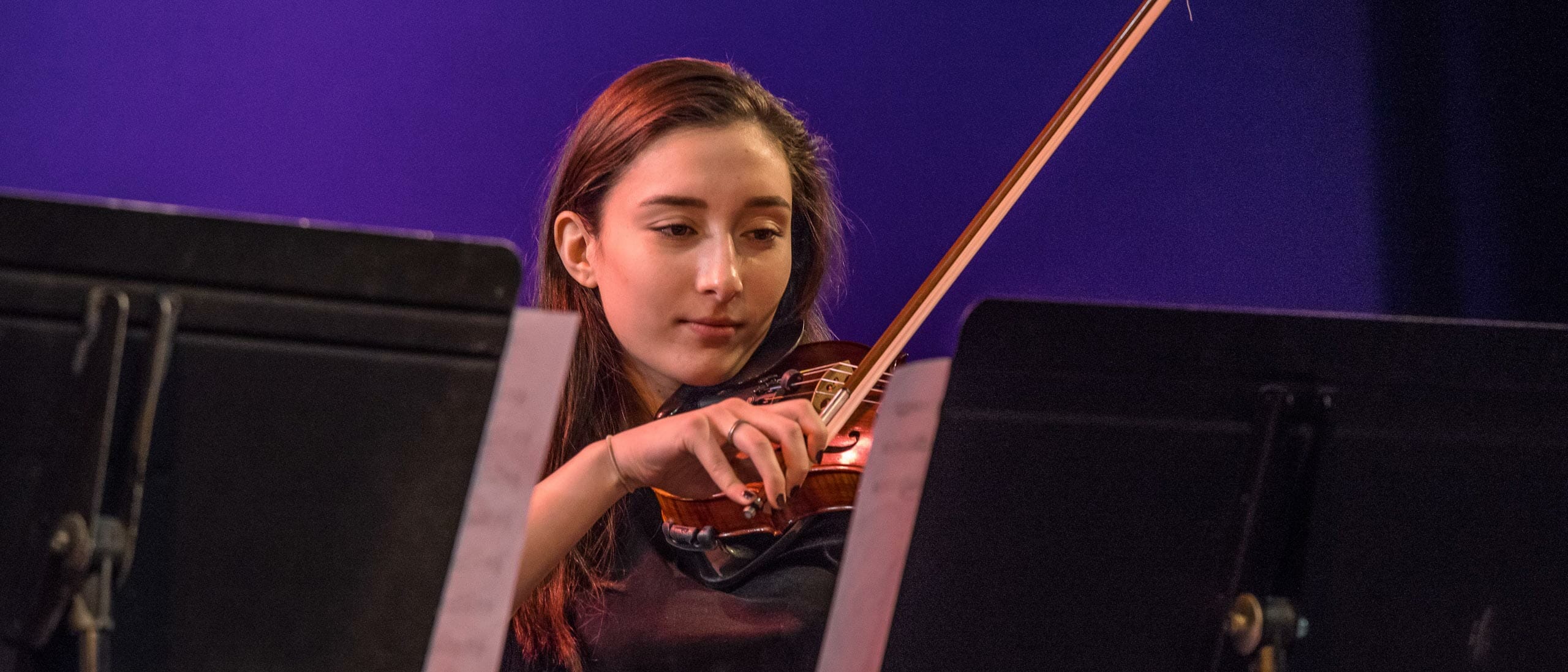 Female student playing the violin on stage