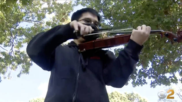A boy with a mask playing the violin