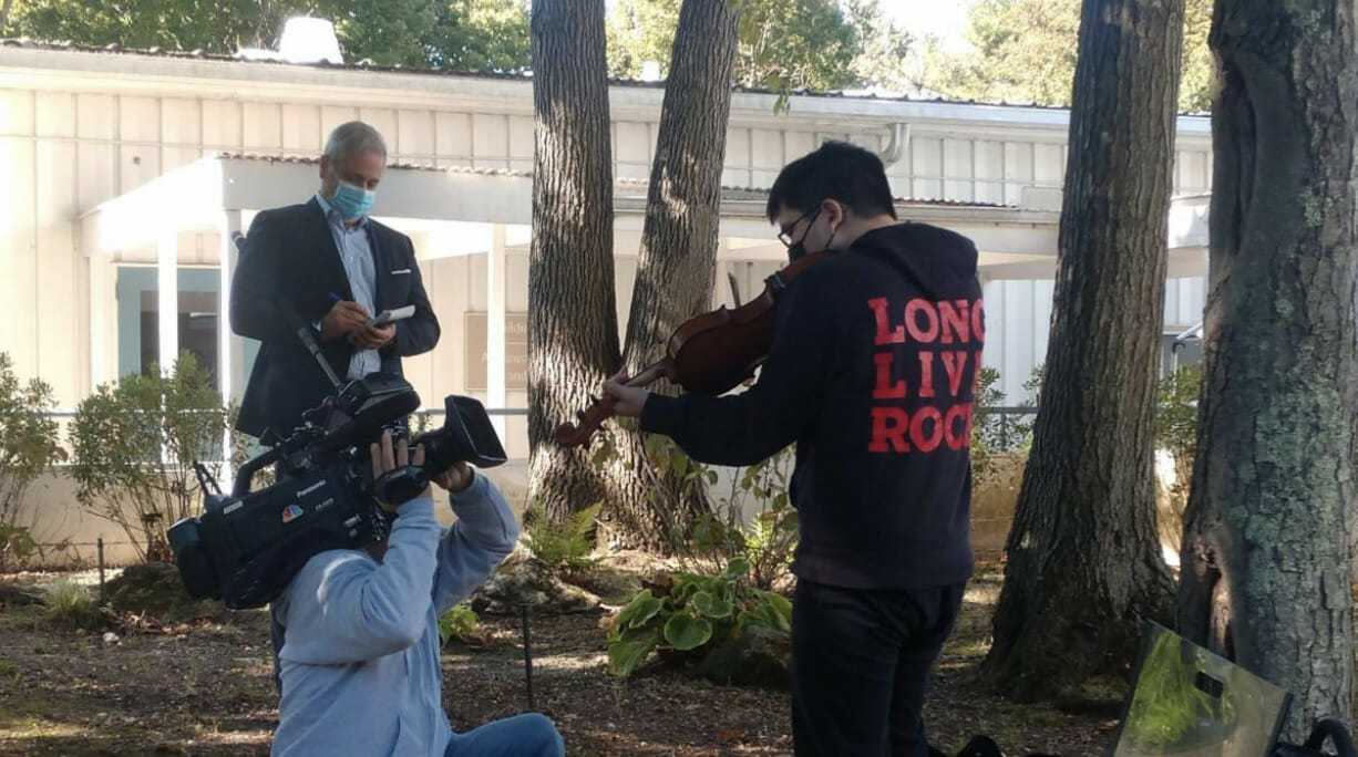 LIHSA student being filmed while playing the violin