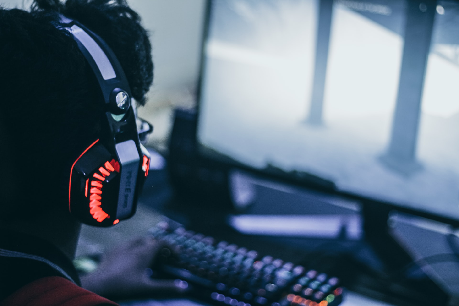 person wearing headphones while looking at a computer screen playing a video game