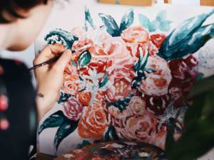 woman painting flowers on an easel