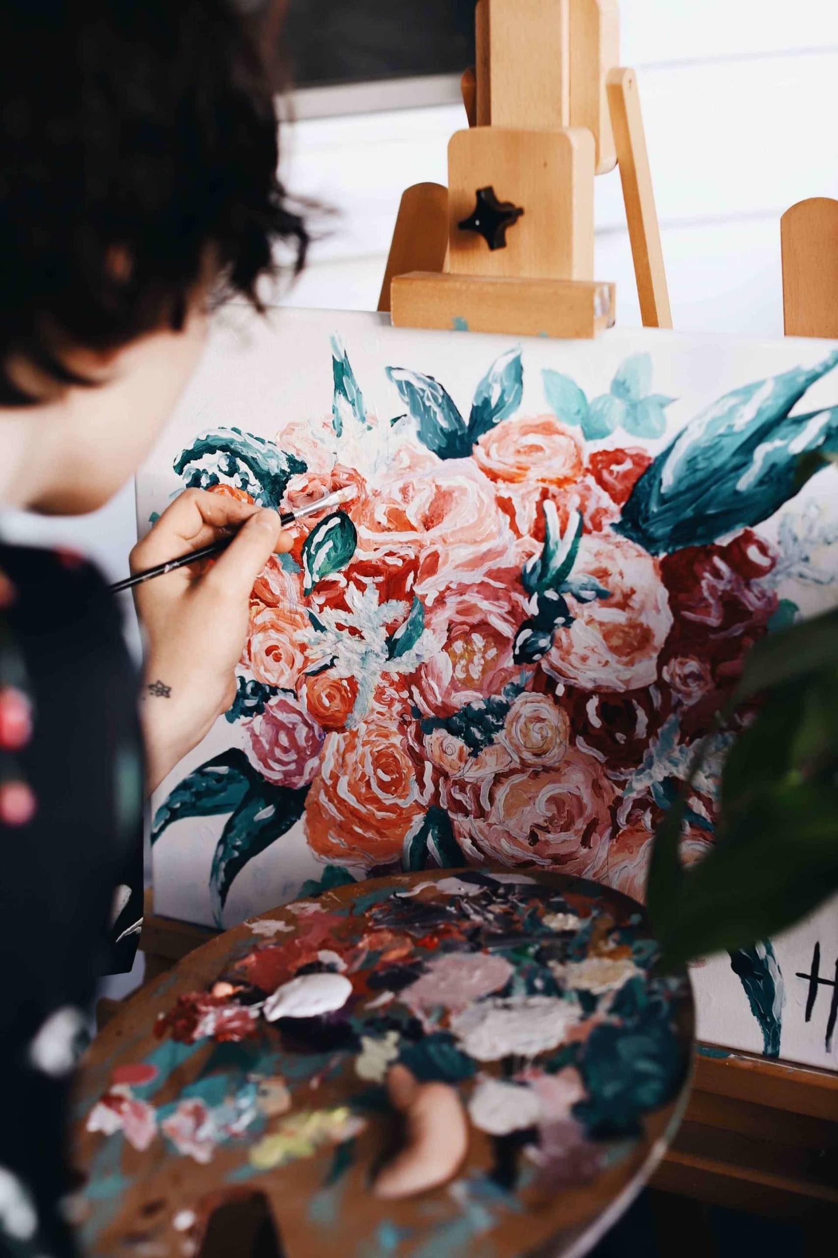 woman painting flowers on an easel