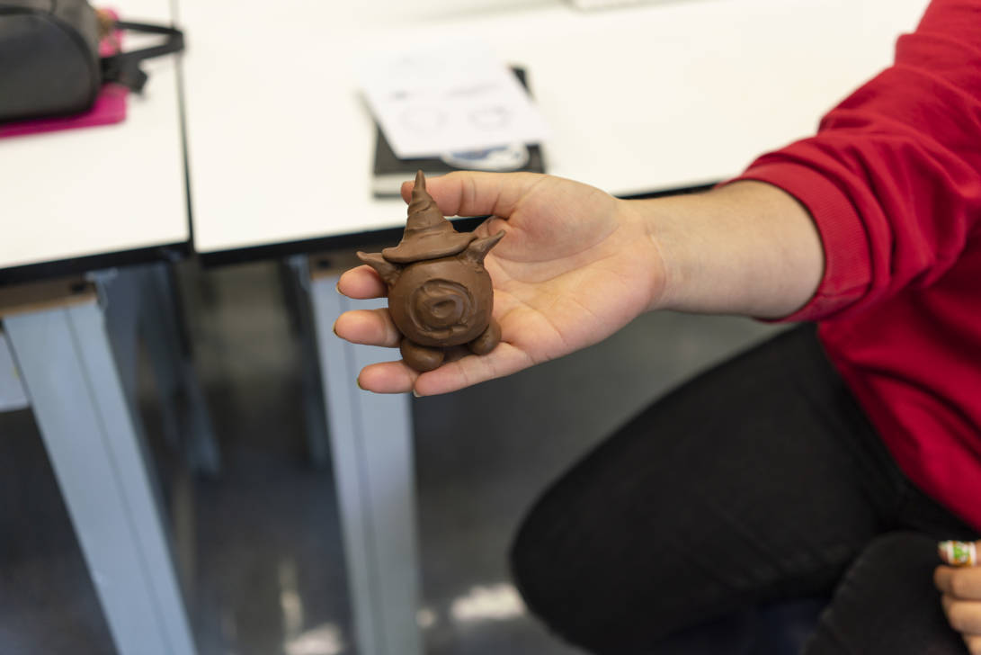 student holding a brown clay statute