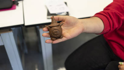 student holding a brown clay statute