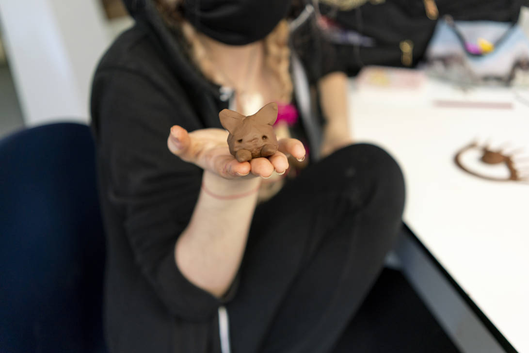 student holding a clay sculpture