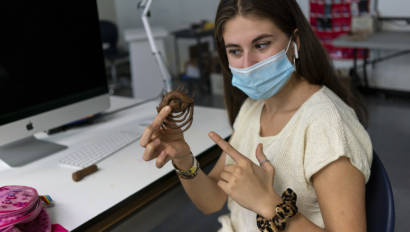 student holding up and pointing at their sculpture